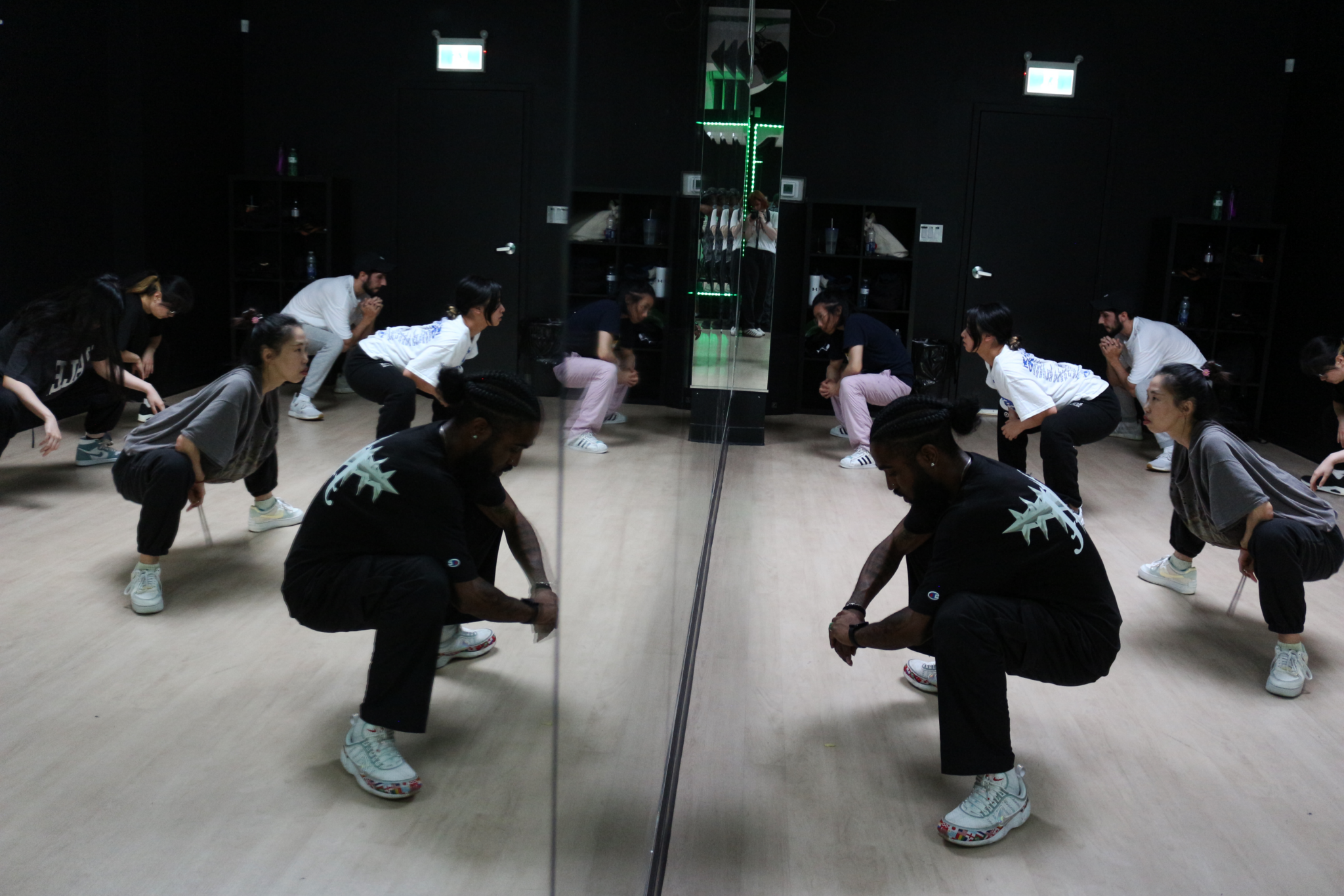 Dance students squat during a routine in a dance class.