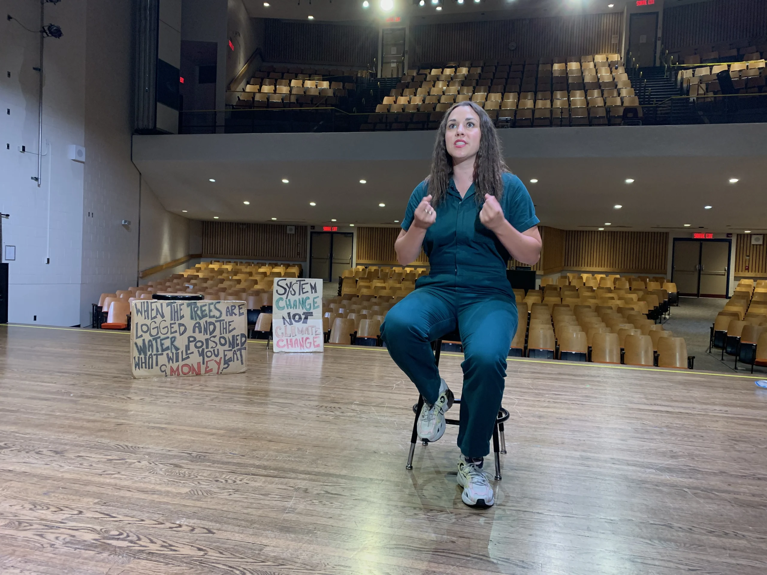Emma Bartolomucci sits in her green suit onstage at Saint-Frère-André Catholic Secondary School.