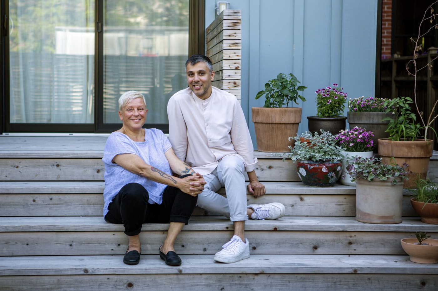 Lesli (left) and Parimal (right) sit on the stairs next to potted plants