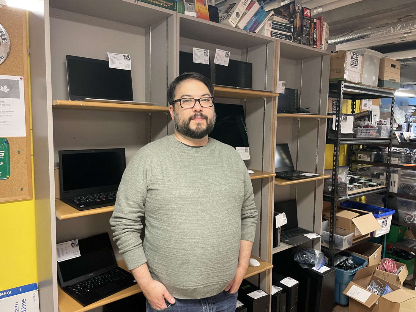 Ryan Fukunaga, executive director of Free Geek Toronto, stands by a shelf of refurbished devices, reducing e-waste.