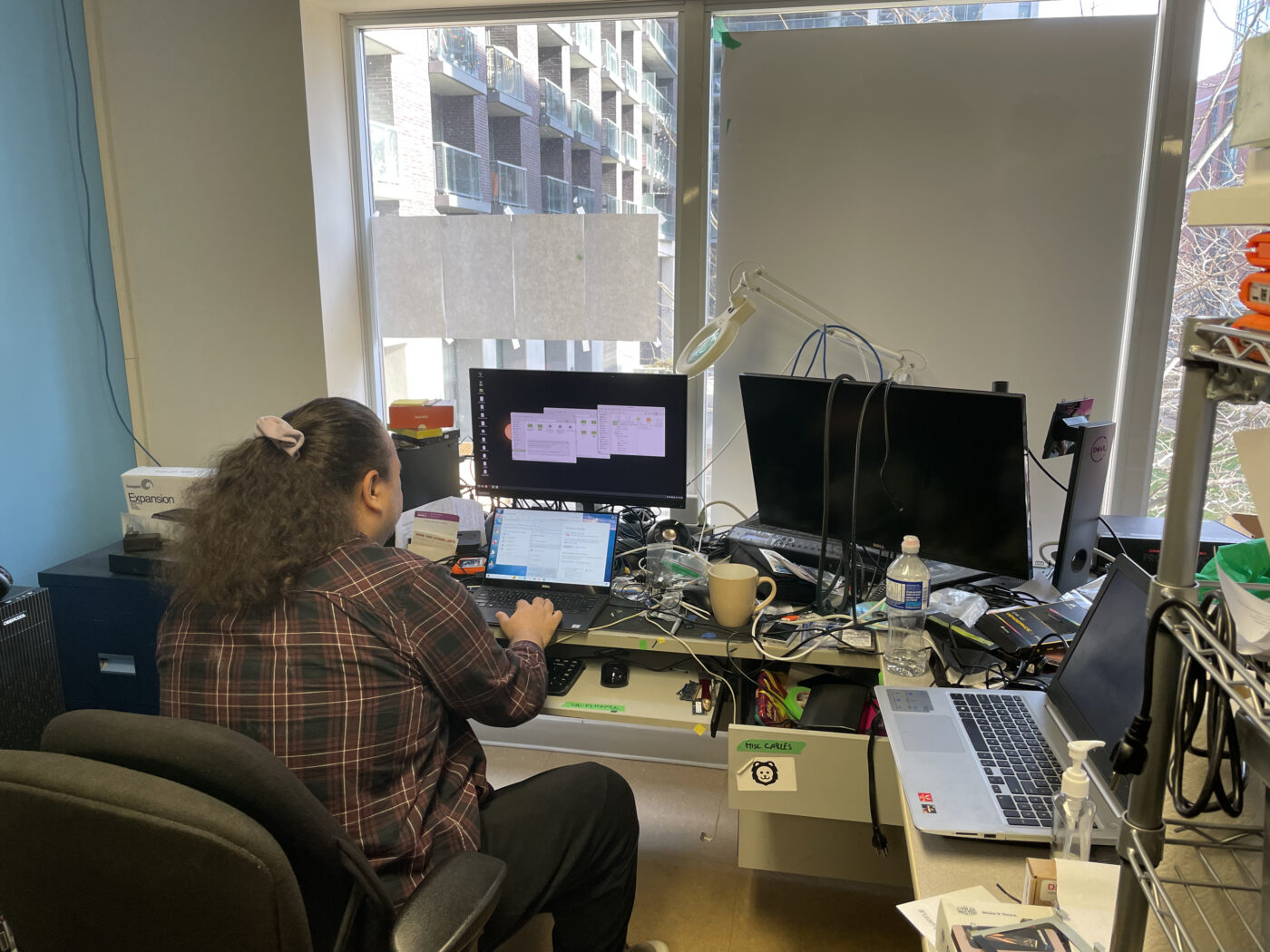 Emma Fawkes, reuse manager at Free Geek Toronto, sits down to fix a computer at their desk inside the store, reducing e-waste.