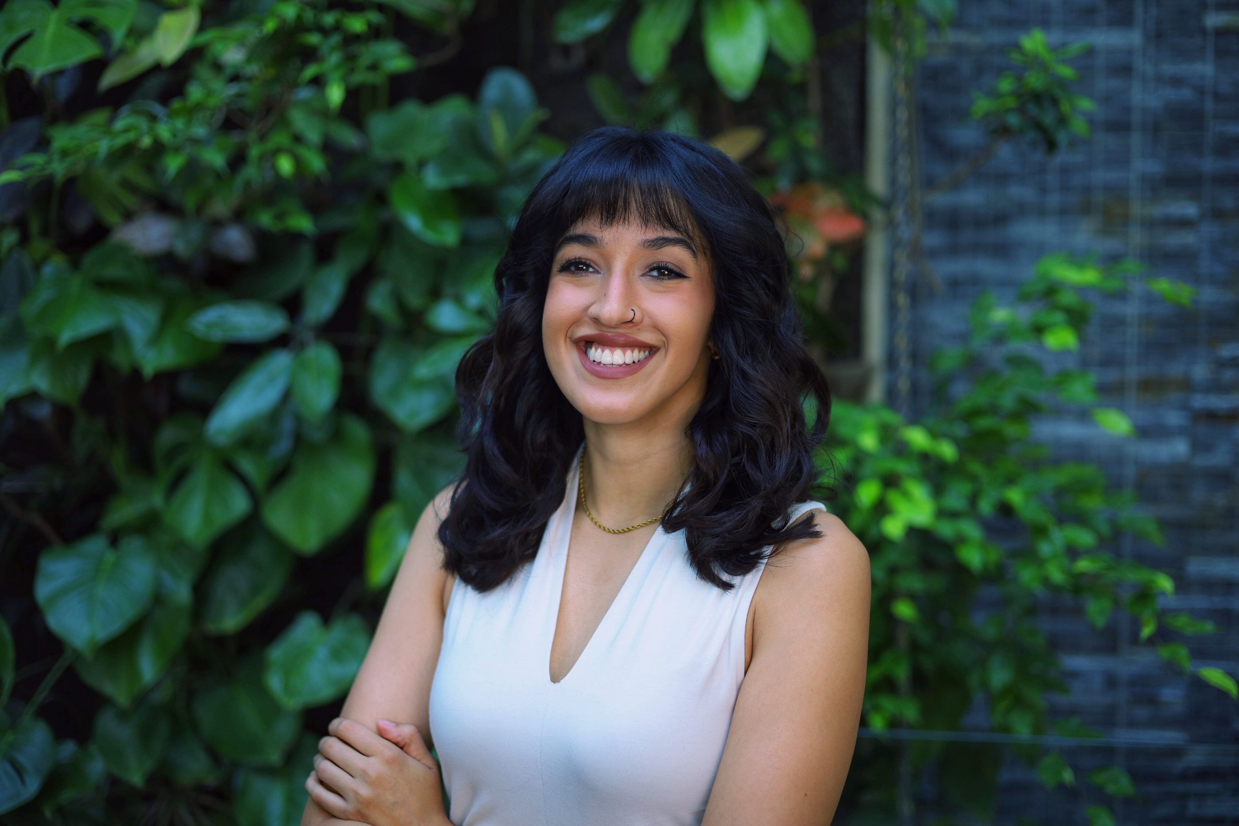 Portrait of Fizza Khalid standing in front of a wall of foliage.