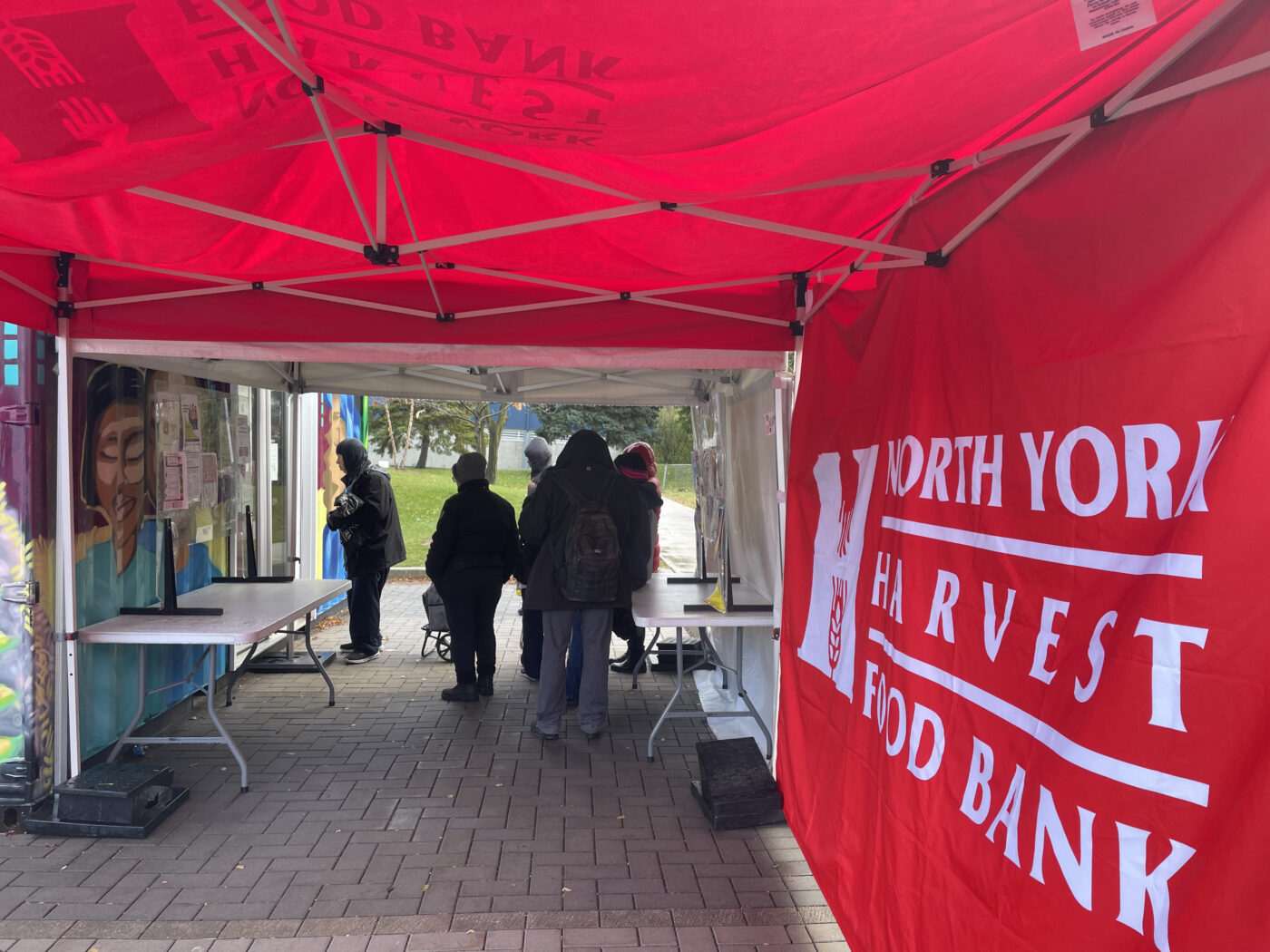 Jamestown residents stand in line outside the food bank inside a shipping container.