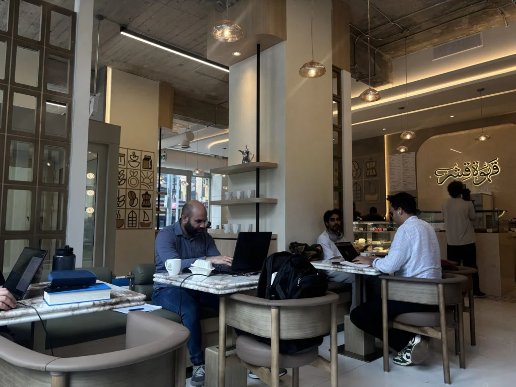 People working at Qishr Coffee House