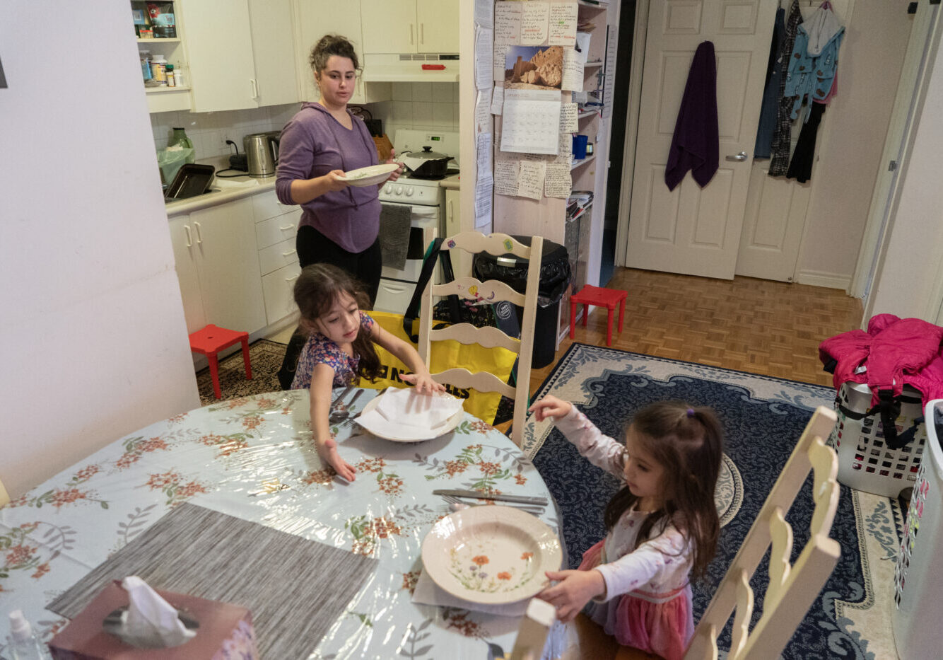 Lilianna, Katalinna(right) and thier mother Juilanna Eftekhari set the table for dinner in East York, Canada, on January 17, 2025.  Julianna Efekhari explains " the girls always help set the table for dinner. Lilianna even knows how to make breakfast and cook eggs." She continues; "we just want the best for them and its hard"