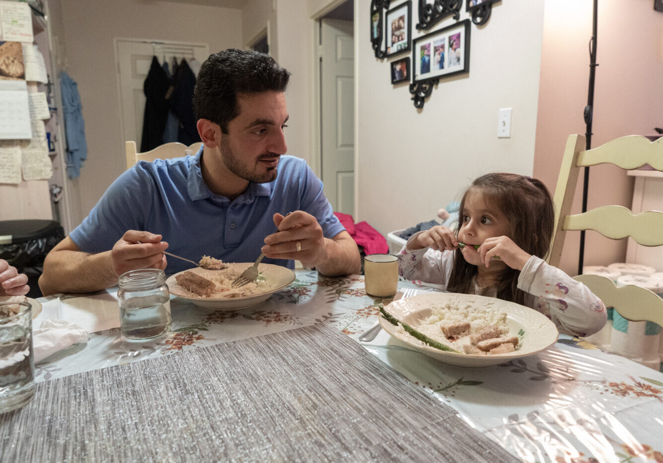 Katalinna  plays during her father Behnam Eftekhari watches in East York, Canada, on January 17, 2025. Ben Efekhari says "The community dinners really help. Grocery costs have gone up a lot. Sometimes the community dinners have some extra produce or pasta and it helps the rest of the week."