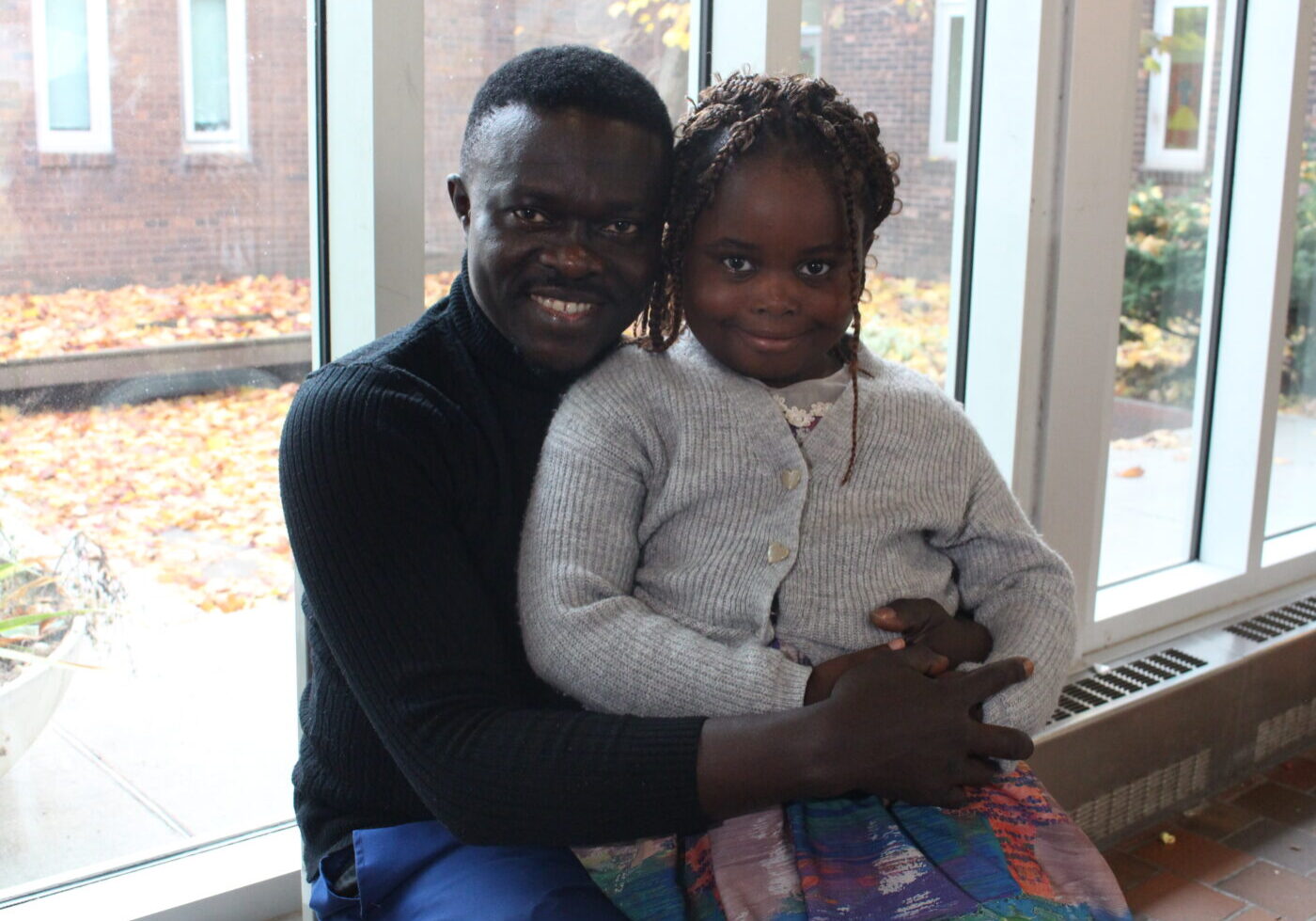 Felix Egbe, a parent at The Reading Partnership for Parents program, sits with his daughter Isabelle Egbe.