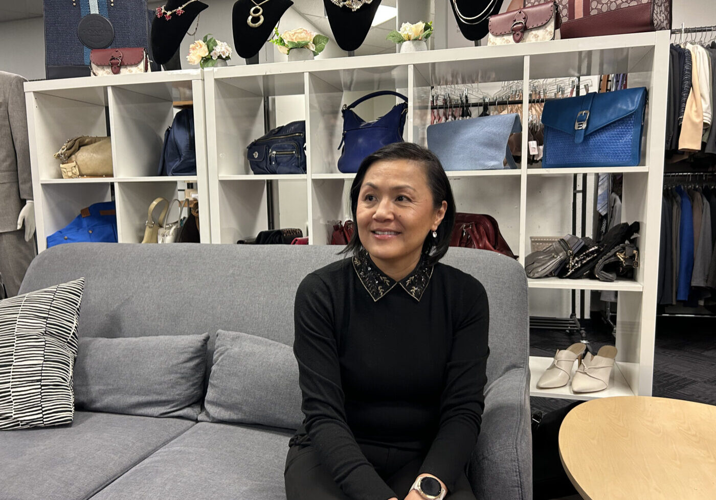 Lichu Chen sitting on a grey couch at the Dress for Success boutique.