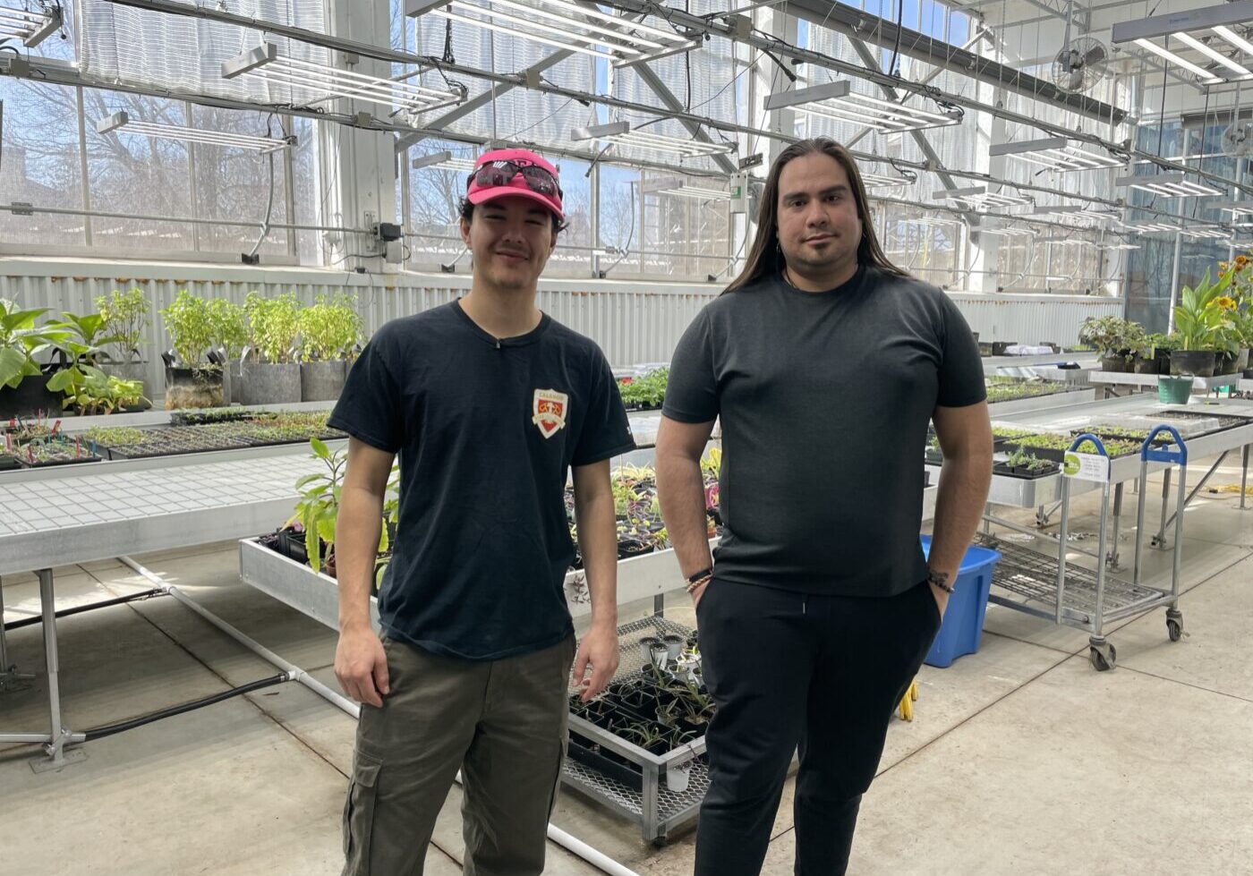 Mashkikiiaki'ng garden coordinators Samuel Wong (pictured left) and Magpie Arancibia (pictured right) stand in The Stop’s greenhouse.