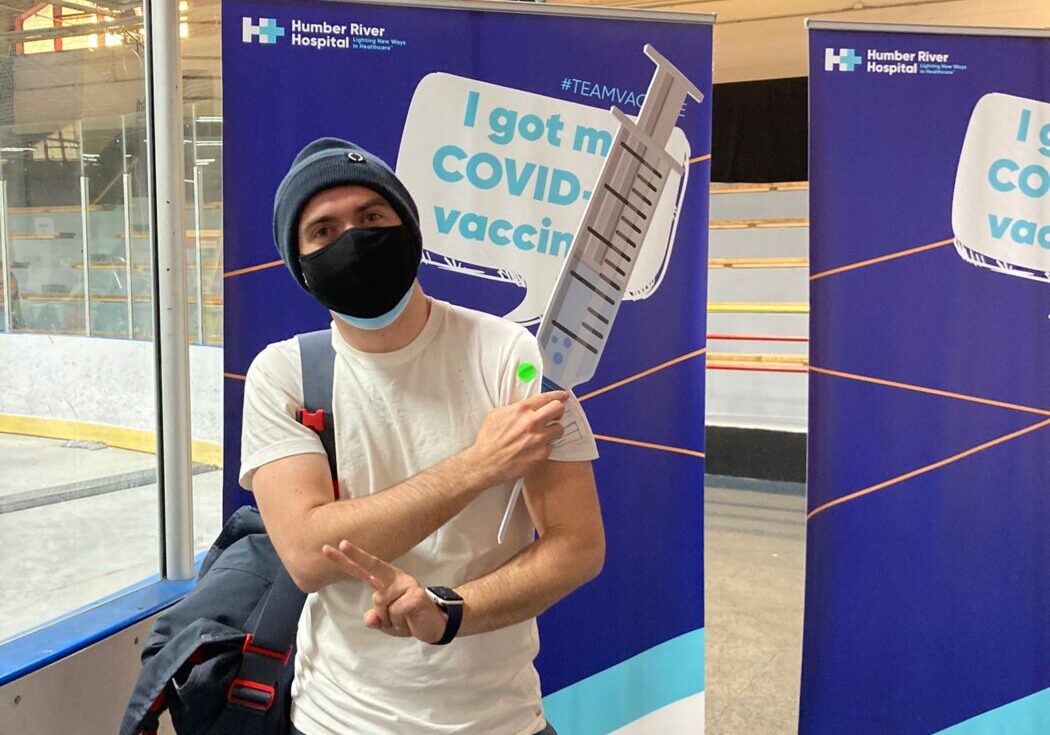 A person in a mask stands in front of a sign that says "I got my COVID vaccine." Sebastian Tansil/The Green Line.